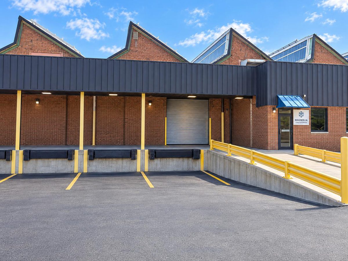 Loading dock bays with bumpers, a roll-up door and yellow safety guardrails outside the building